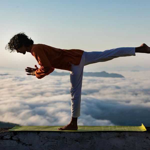 Silhouette of a man stretching at sunrise, representing well-being.